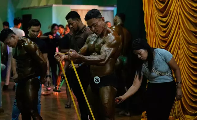 Contestants prepare at backstage during their bodybuilding competition to mark International Olympic Day at the Myanmar Convention Center in Yangon, Myanmar, Saturday, June 28, 2025. (AP Photo/Thein Zaw)