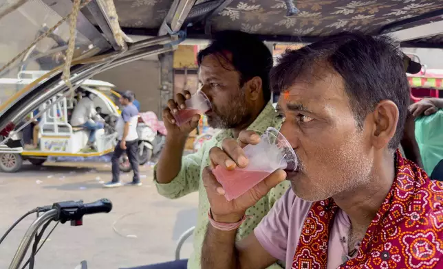 Passengers traveling in a vehicle stop for a free roadside drink on a hot summer day in Prayagraj in the northern state of Uttar Pradesh, India, Tuesday, June 10, 2025. (AP Photo/Rajesh Kumar Singh)