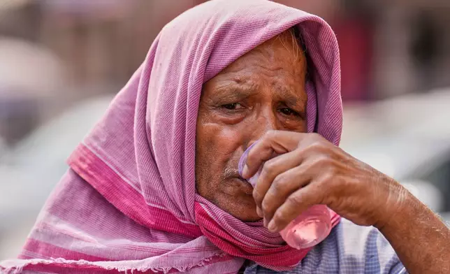 A passenger traveling in a vehicle stops for a free roadside drink on a hot summer day in Prayagraj in the northern state of Uttar Pradesh, India, Tuesday, June 10, 2025. (AP Photo/Rajesh Kumar Singh)