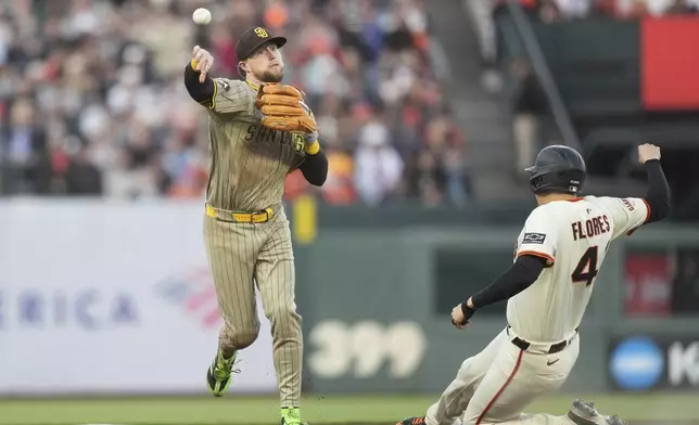 San Diego Padres second baseman Jake Cronenworth, left, throws to first base after forcing San Francisco Giants' Wilmer Flores, right, out at second base on a double play hit into by Matt Chapman during the third inning of a baseball game in San Francisco, Monday, June 2, 2025. (AP Photo/Jeff Chiu)