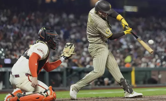 San Diego Padres' Jose Iglesias, right, hits a sacrifice fly next to San Francisco Giants catcher Patrick Bailey, left, that scored Jake Cronenworth during the tenth inning of a baseball game in San Francisco, Monday, June 2, 2025. (AP Photo/Jeff Chiu)