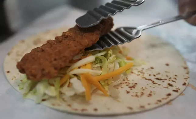 Charles L. Krumsiek, a McDonald's chef, puts a chicken on a tortilla to make a snack wrap at McDonald's Headquarter in Chicago, Thursday, May 29, 2025. (AP Photo/Nam Y. Huh)