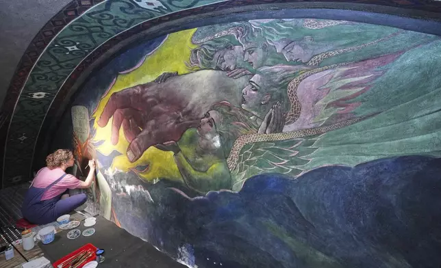 Art conservator Jessica Keister works on a mural by Maxo Vanka depicting the hand of God handing a tablet to Moses, inside St. Nicholas Croatian Catholic Church in Millvale, Pa., Wednesday, Feb. 19, 2025. (AP Photo/Gene J. Puskar)