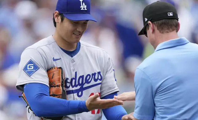 Los Angeles Dodgers starting pitcher Shohei Ohtani is checked by third base umpire Alex Tosi after pitching in the first inning of a baseball game against the Kansas City Royals, Saturday, June 28, 2025, in Kansas City, Mo. (AP Photo/Charlie Riedel)