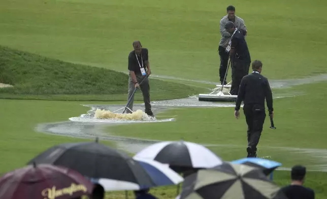 Grounds keepers clear water from the course during a weather delay in the final round of the U.S. Open golf tournament at Oakmont Country Club Sunday, June 15, 2025, in Oakmont, Pa. (AP Photo/Gene J. Puskar)