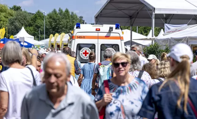 An ambulance from the German Red Cross drives through the crowd after a billboard came loose from the stands and fell into the spectator area during the Halle ATP tennis tournament in Halle, Germany, Wednesday, June 18, 2025. (David Inderlied/dpa via AP)