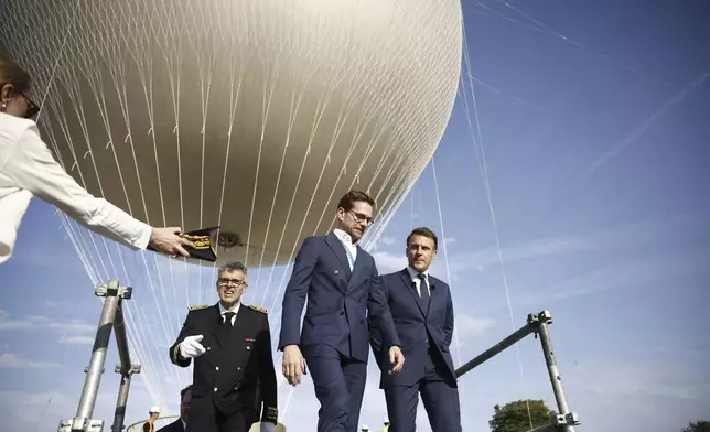 French President Emmanuel Macron, right, visits the site of the reinstallation of the Olympic cauldron at the Tuileries Garden in Paris, Thursday, June 12, 2025. (Yoan Valat/Pool Photo via AP)