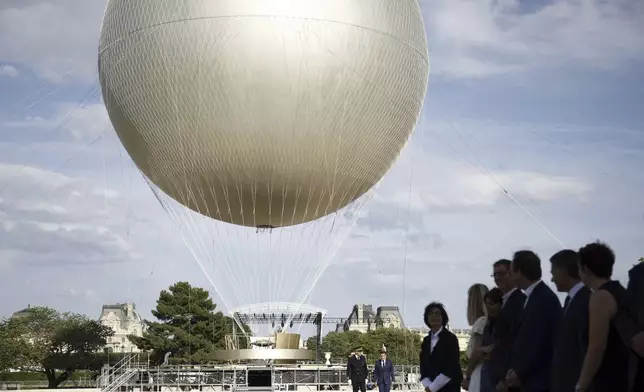 French President Emmanuel Macron, right background, visits the site of the reinstallation of the Olympic cauldron at the Tuileries Garden in Paris, Thursday, June 12, 2025. (Yoan Valat/Pool Photo via AP)