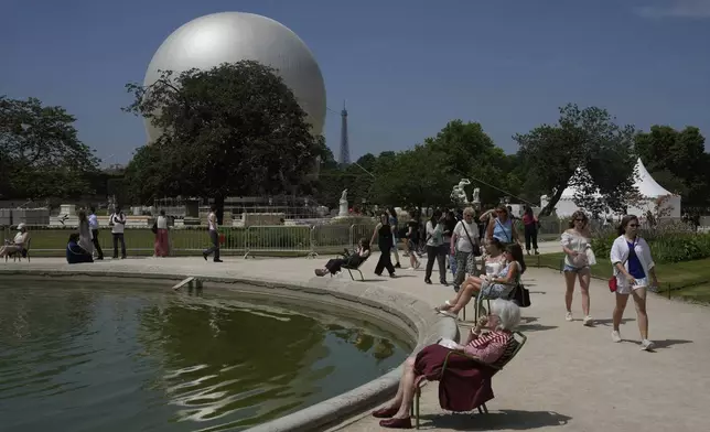 People walk past the Olympic cauldron at the Tuileries Gardens, ahead of its nightly summer relaunch starting June 21, in Paris, Thursday, June 12, 2025. (AP Photo/Michel Euler)