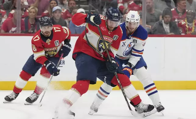 Florida Panthers defenseman Nate Schmidt (88) and Edmonton Oilers defenseman John Klingberg (36) go after the puck during the first period of Game 6 of the NHL hockey Stanley Cup Final Tuesday, June 17, 2025, in Sunrise, Fla. (AP Photo/Lynne Sladky)