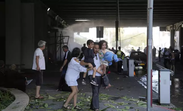People evacuate after a missile launched from Iran struck in Haifa, Israel, Friday, June 20, 2025. (AP Photo/Baz Ratner)