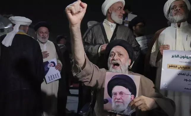 An Iraqi Shiite cleric holds a portrait of Iran's Supreme Leader Ayatollah Ali Khamenei during a protest against Israeli attacks on multiple cities across Iran, at a bridge leading to the fortified Green Zone where the U.S. Embassy is located in Baghdad, Iraq, Thursday, June 19, 2025. (AP Photo/Hadi Mizban)