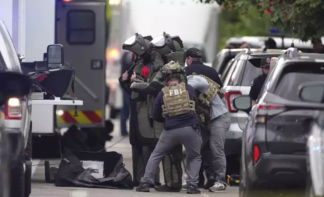 Law enforcement officials dress in protective gear to investigate after an attack on the Pearl Street Mall Sunday, June 1, 2025, in Boulder, Colo. (AP Photo/David Zalubowski)