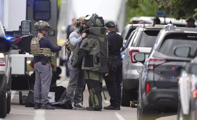 Law enforcement officials dress up in protective gear to investigative an attack on the Pearl Street Mall, Sunday, June 1, 2025, in Boulder, Colo. (AP Photo/David Zalubowski)