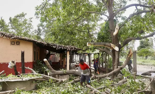 Residents remove debris after the passing of Hurricane Erick, near Charco Redondo, Oaxaca state, Mexico, Thursday, June 19, 2025. (AP Photo/Luis Alberto Cruz)