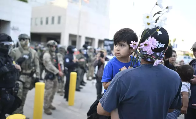 Tony Robles holds his son Malakey during a protest outside the Federal Building on Friday, June 13, 2025, in Los Angeles. (AP Photo/Wally Skalij)