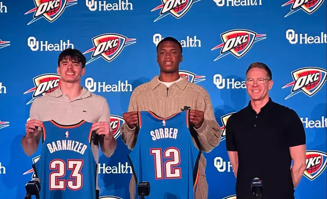 Oklahoma City Thunder draft picks, from left, Brooks Barnhizer and Thomas Sorber, center, pose with general manager Sam Presti during an NBA basketball news conference, Saturday, June 28, 2025, in Oklahoma City. (AP Photo/Cliff Brunt)