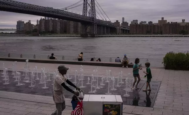 People walk around a water fountain at Domino Park, Friday, June 27, 2025, in the Brooklyn borough of New York. (AP Photo/Yuki Iwamura)