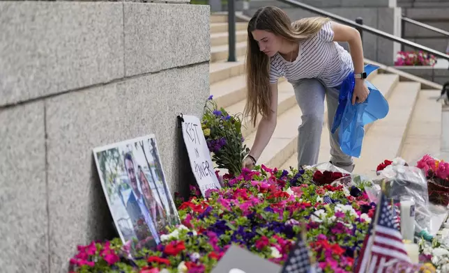Claire Stein places flowers at a makeshift memorial for Minnesota state Rep. Melissa Hortman and her husband Mark at the state Capitol, Sunday, June 15, 2025, in St. Paul, Minn. (AP Photo/George Walker IV)