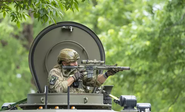 An amed FBI agent in an armored vehicle takes part in the search for an active shooter, sweeping a neighborhood adjacent to the home of Minnesota DFL State Representative Melissa Hortman, in Brooklyn Park, Minn., Saturday, June 14, 2025. (Alex Kormann/Star Tribune via AP)