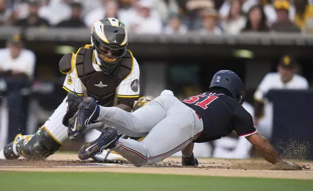 Washington Nationals' Daylen Lile, right, slides into home plate, scoring off a sacrifice bunt by Jacob Young as San Diego Padres catcher Martín Maldonado is late with the tag during the second inning of a baseball game Tuesday, June 24, 2025, in San Diego. (AP Photo/Gregory Bull)