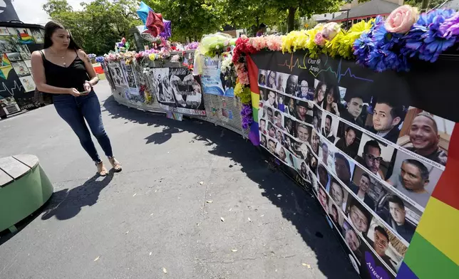 FILE - A visitor looks over a display with the photos and names of the 49 victims that died at the Pulse nightclub memorial, June 11, 2021, in Orlando, Fla. (AP Photo/John Raoux, file)