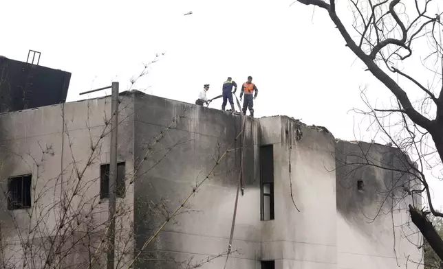 Firefighters and other personnel work on a rooftop at the site of an Air India plane crash in Ahmedabad, India, Friday, June 13, 2025. (AP Photo/Rafiq Maqbool)