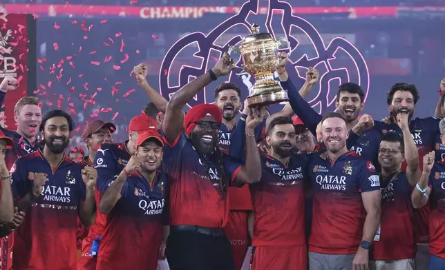 Royal Challengers Bengaluru's Virat Kohli, center, flanked with former teammates Chris Gayle, in red turban, and AB de Villiers after their win in the Indian Premier League final cricket match against Punjab Kings at Narendra Modi Stadium in Ahmedabad, India, Wednesday, June 4, 2025. (AP Photo/Ajit Solanki)