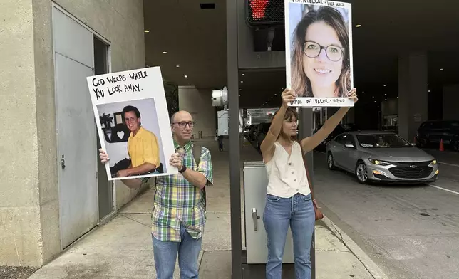 Barry Bowen, left, and Johnna Harris hold signs honoring the recently deceased Gareld Duane Rollins and Jennifer Lyell, whistleblowers who faulted the Southern Baptist Convention's handling of sexual abuse, on Tuesday, June 10, 2025, outside the Kay Bailey Hutchison Convention Center in Dallas, Texas. (AP Photo/Peter Smith)