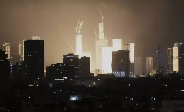 An explosion caused by a projectile strike illuminates the skyline in Tel Aviv, Israel, early Saturday, June 14, 2025. (AP Photo/Leo Correa)