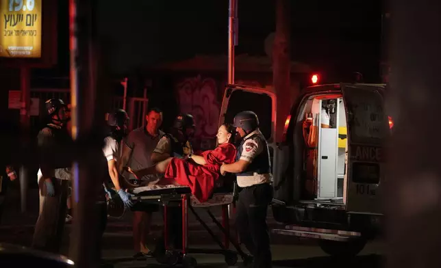 Paramedics evacuate a wounded woman from a building struck by a missile fired from Iran, in Tel Aviv, Israel, on Friday, June 13, 2025. (AP Photo/Tomer Appelbaum)