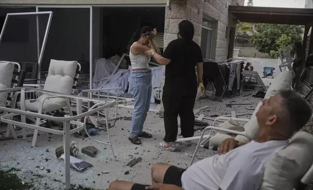 Residents react after their home was struck by a missile launched from Iran, in Rishon Lezion, Israel, on Saturday, June 14, 2025. (AP Photo/Ohad Zwigenberg)