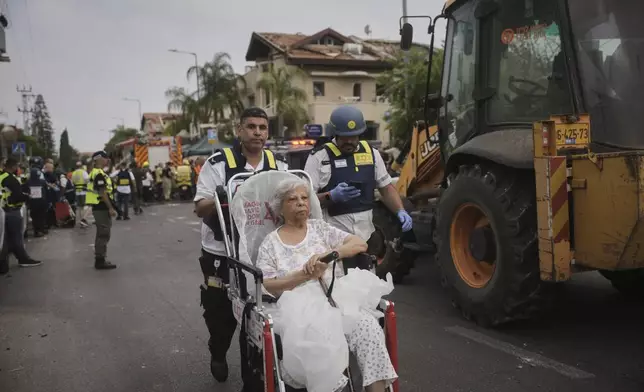 Paramedics evacuate a woman from a site that was struck by a missile fired from Iran, in Rishon Lezion, Israel, on Saturday, June 14, 2025. (AP Photo/Ohad Zwigenberg)