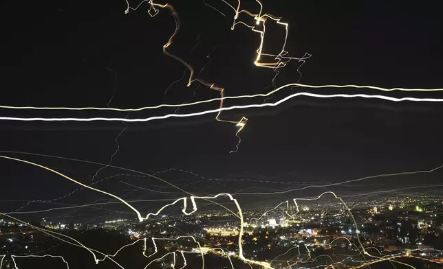 In this image taken with a slow shutter speed, projectiles light up the night sky over Jerusalem during an Iranian missile attack, Friday, June 13, 2025, in Jerusalem. (AP Photo/Mahmoud Illean)