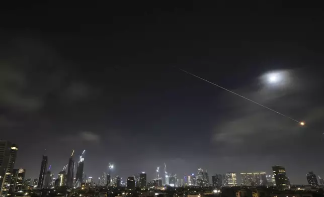 The trace of a projectile illuminates the sky in Tel Aviv, Israel, early Saturday, June 14, 2025. (AP Photo/Leo Correa)