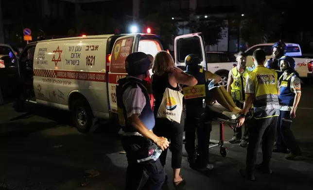 Paramedics evacuate a wounded person from a building struck by a missile fired from Iran, in Tel Aviv, Israel, on Friday, June 13, 2025. (AP Photo/Tomer Appelbaum)