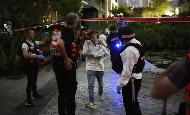 People evacuate from a building struck by a missile fired from Iran, in Tel Aviv, Israel, on Friday, June 13, 2025. (AP Photo/Tomer Appelbaum)