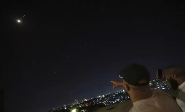People watch to traces over Jerusalem during a missile attack alert, on Friday, June 13, 2025. (AP Photo/Ohad Zwigenberg)