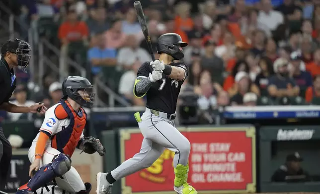 Chicago White Sox's Edgar Quero (7) hits a two-run single as Houston Astros catcher Victor Caratini watches during the third inning of a baseball game Tuesday, June 10, 2025, in Houston. (AP Photo/David J. Phillip)