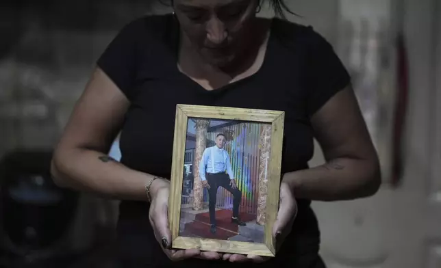 Claudia Caballero poses with a photo of her late son Alexis Almiron, a cancer patient who tried to get medication that had been covered by federal agency DADSE, but which President Javier Milei dissolved, in the outskirts of Buenos Aires, Argentina, Monday, May 5, 2025. (AP Photo/Natacha Pisarenko)