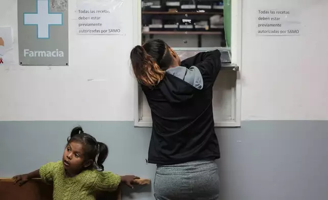A woman leans on a counter while waiting to receive free medicine at the Rodolfo Rossi Hospital in La Plata, Argentina, Thursday, May 8, 2025. According to experts, government workers and advocates, President Javier Milei's cutbacks have overwhelmed the nation’s public hospitals, upended vaccination efforts and taken a toll on the country’s poor and unemployed. (AP Photo/Natacha Pisarenko)