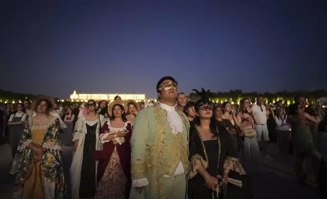 Costumed guests watch fireworks in the gardens of the Versailles castle before the Great Masked Ball in Versailles, outside Paris, Saturday, June 21, 2025. (AP Photo/Christophe Ena)