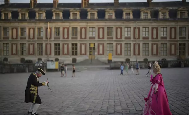 Costumed guests take photos as they arrive at the Great Masked Ball in Versailles, outside Paris, Saturday, June 21, 2025. (AP Photo/Christophe Ena)
