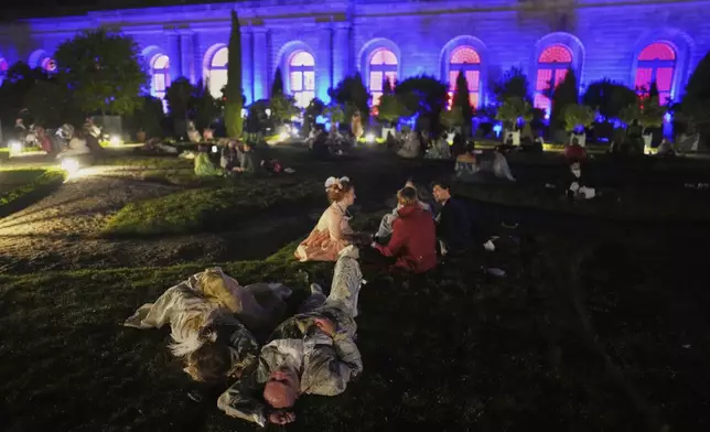 Costumed guests take a break as they attend the Great Masked Ball in the Orangerie of the Versailles castle, outside Paris, Sunday, June 22, 2025. (AP Photo/Christophe Ena)