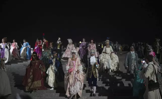 Costumed guests arrive for the Great Masked Ball in the Orangerie of the Versailles castle, outside Paris, Saturday, June 21, 2025. (AP Photo/Christophe Ena)