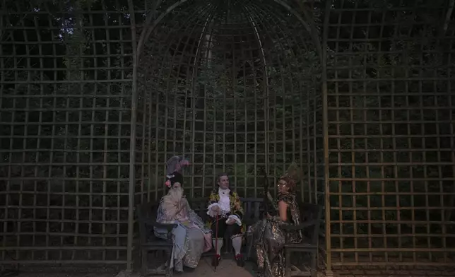 Costumed guests sit in the gardens of the Versailles castle before the Great Masked Ball in Versailles, outside Paris, Saturday, June 21, 2025. (AP Photo/Christophe Ena)