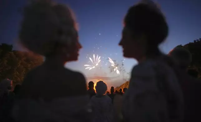 Costumed guests watch fireworks in the gardens of the Versailles castle before the Great Masked Ball in Versailles, outside Paris, Saturday, June 21, 2025. (AP Photo/Christophe Ena)