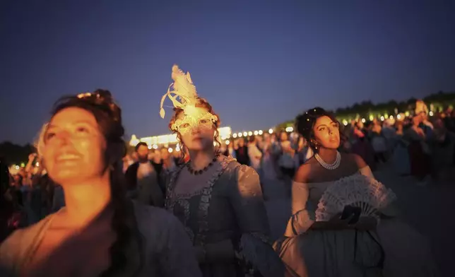 Costumed guests watch fireworks in the gardens of the Versailles castle before the Great Masked Ball in Versailles, outside Paris, Saturday, June 21, 2025. (AP Photo/Christophe Ena)