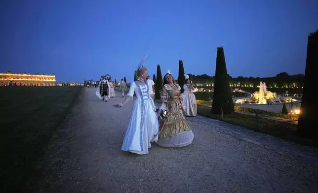 Costumed guests run in the gardens of the Versailles castle before the Great Masked Ball in Versailles, outside Paris, Saturday, June 21, 2025. (AP Photo/Christophe Ena)