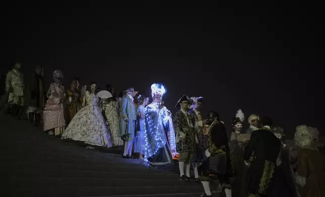 Costumed guests arrive for the Great Masked Ball in the Orangerie of the Versailles castle, outside Paris, Saturday, June 21, 2025. (AP Photo/Christophe Ena)